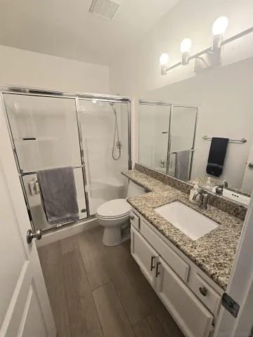 a bathroom with a granite countertop sink a toilet and a mirror