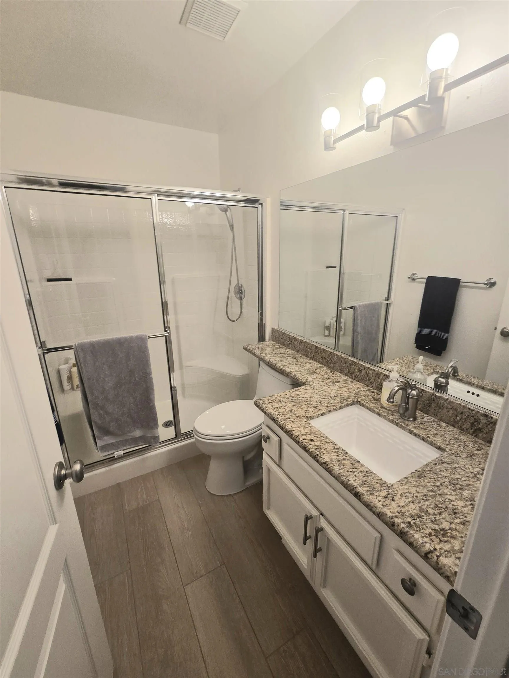 4802 Baroque Terrace Oceanside, CA 92057 - Photo 19 of 26 a bathroom with a granite countertop sink a toilet and a mirror