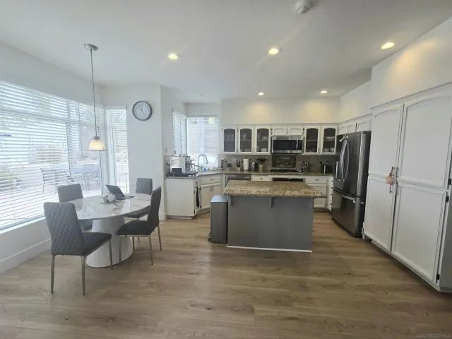 a kitchen with stainless steel appliances kitchen island granite countertop a table chairs and a refrigerator