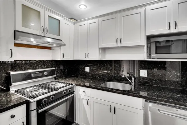a kitchen with granite countertop a stove and cabinets
