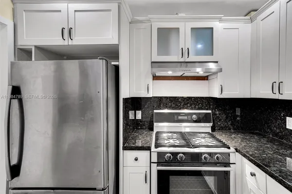 a kitchen with stainless steel appliances granite countertop a refrigerator and a stove
