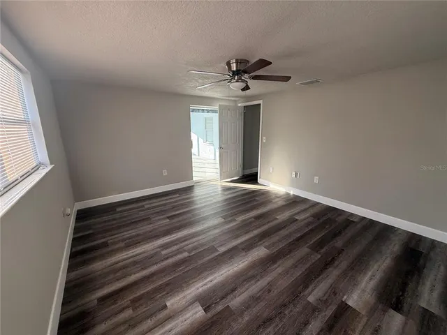 a view of an empty room with window and wooden floor