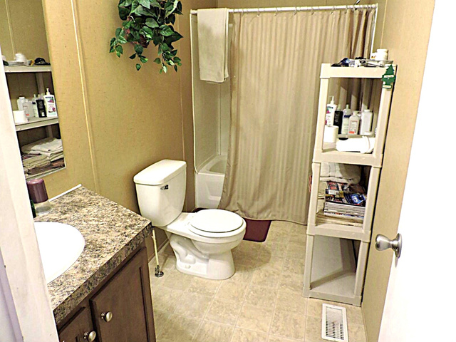 915 North 5000 W Road Hinckley, UT 84635 - Photo 15 of 27 Bathroom featuring a white toilet, built-in tub with shower, and a vanity with an integrated sink and patterned countertop