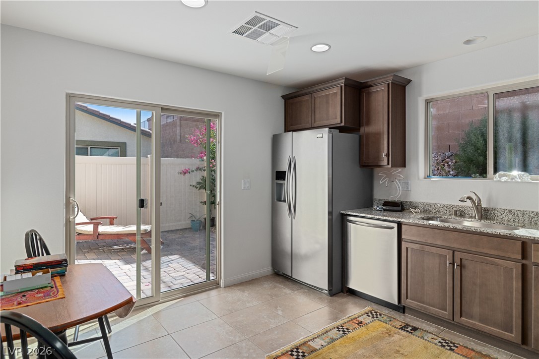 2269 Chandler Ranch Place Laughlin, NV 89029 - Photo 16 of 96 Kitchen featuring stainless steel appliances, dark brown cabinets, light stone countertops, recessed lighting, and light tile patterned flooring
