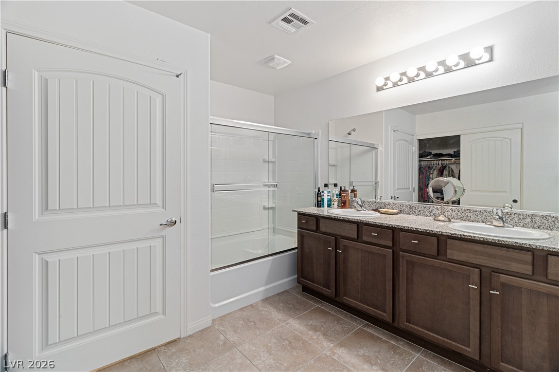 2269 Chandler Ranch Place Laughlin, NV 89029 - Photo 24 of 96 Full Primary bathroom featuring a walk in closet, enclosed tub / shower combo, double vanity, and light tile patterned flooring