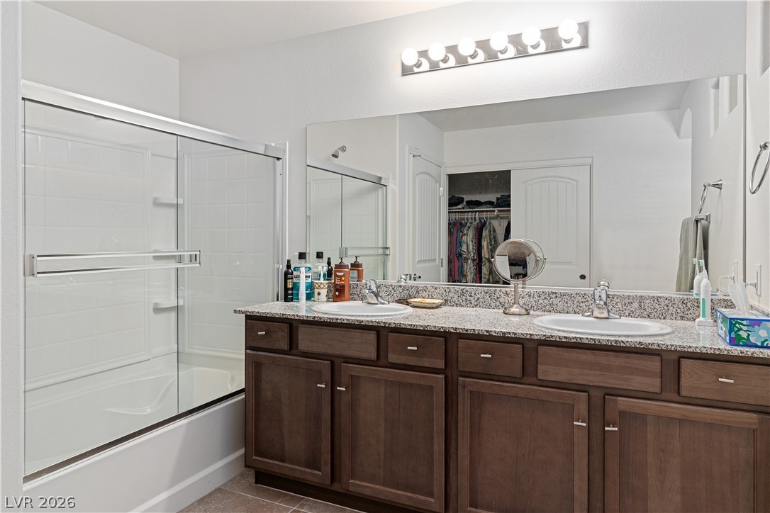 2269 Chandler Ranch Place Laughlin, NV 89029 - Photo 25 of 96 Full Primary bathroom featuring a walk in closet, bath / shower combo with glass door, dark tile patterned flooring, and double vanity