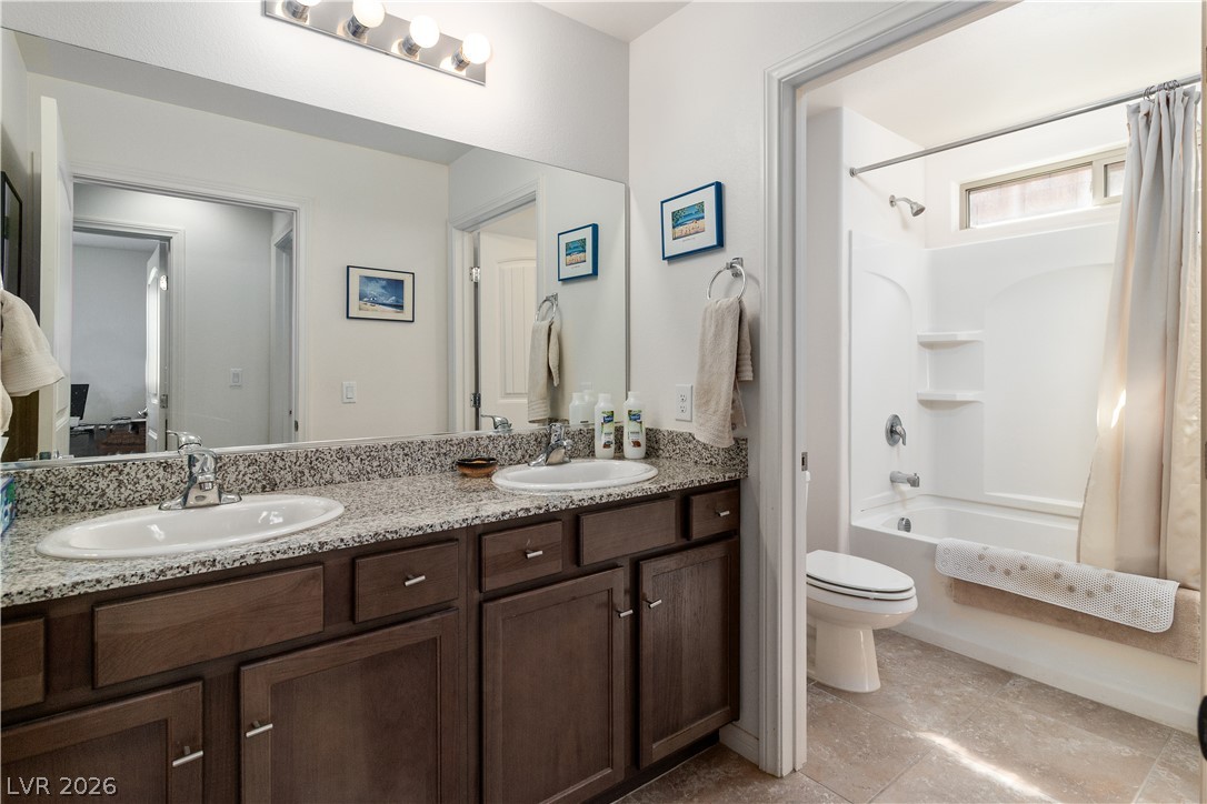 2269 Chandler Ranch Place Laughlin, NV 89029 - Photo 34 of 96 Full Hall bathroom featuring shower / bath combo with shower curtain, double vanity, and light tile patterned floors