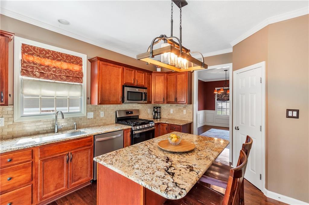 5012 Silver Oaks Drive McKees Rocks, PA 15136 - Photo 10 of 25 a kitchen with stainless steel appliances granite countertop a sink a stove top oven a dining table and chairs with wooden floor
