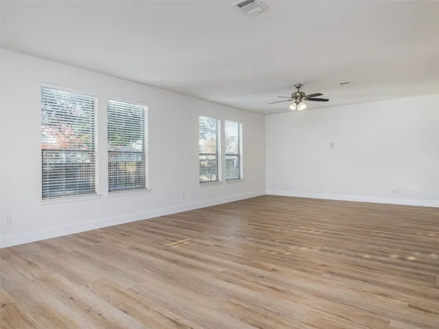an empty room with windows and chandelier fan