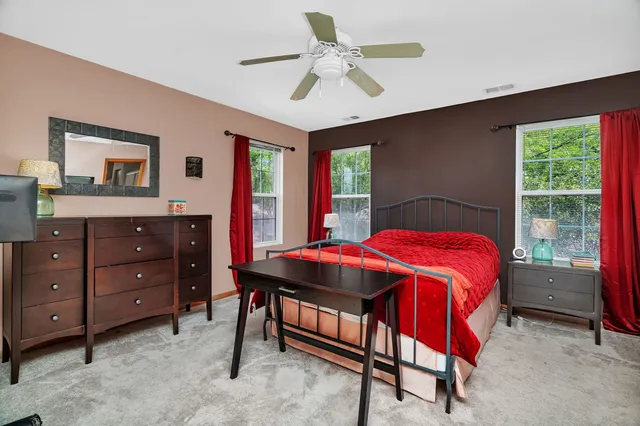 a bedroom with a bed and a dresser next to a window