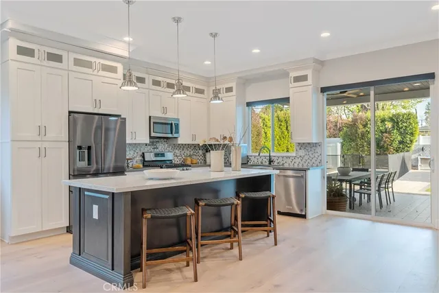 a kitchen with stainless steel appliances granite countertop a table chairs refrigerator and sink