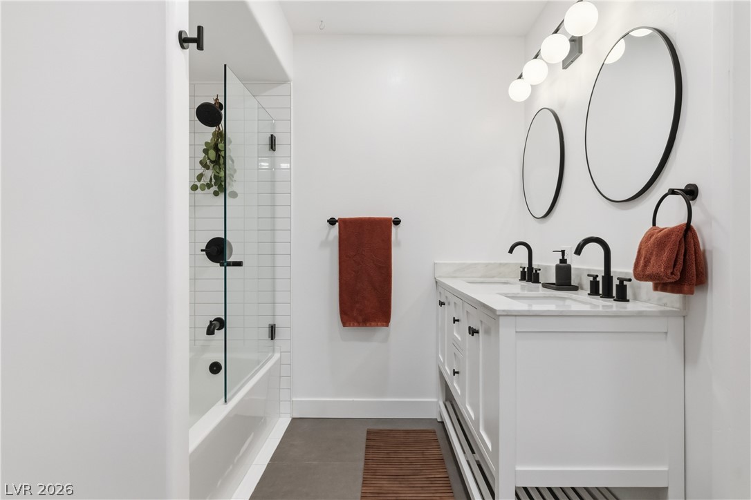 7950 West Flamingo Road, Unit 1180 Las Vegas, NV 89147 - Photo 21 of 26 Sleek, modern bathroom featuring a double vanity with striking black fixtures and a tub shower.