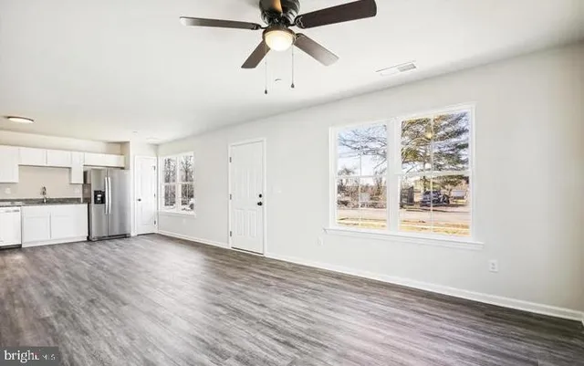 a view of a livingroom with kitchen space and wooden floor