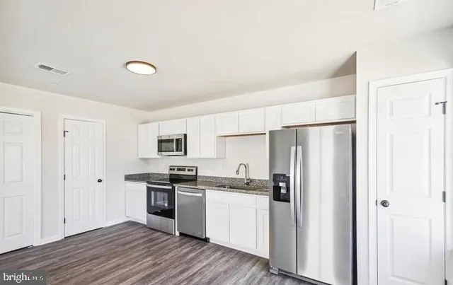 an empty room with wooden floor ceiling fan and windows