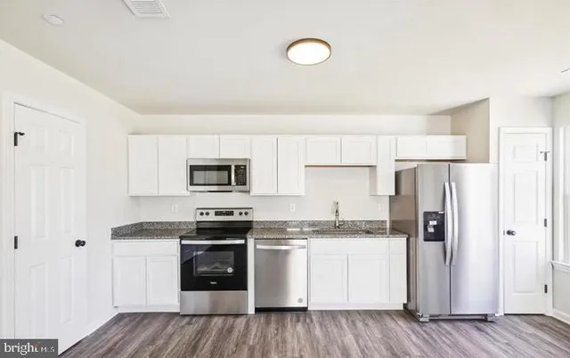 a kitchen with a sink a stove a refrigerator and white cabinets