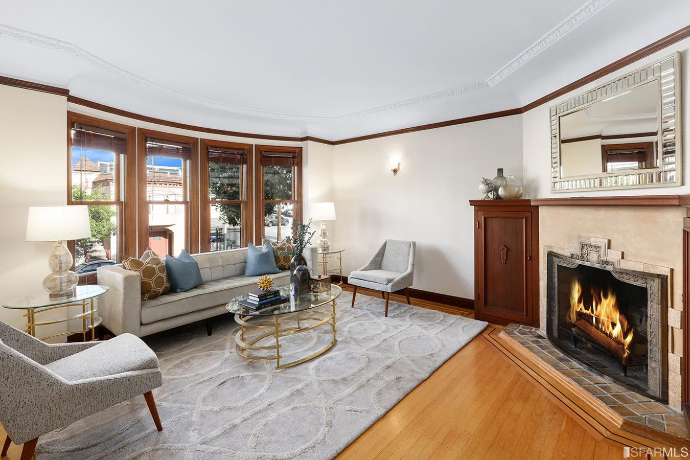 The home boasts an expansive living room  with beautifully preserved period details including elegant paneled doors, inlaid hardwood floors and a wood-burning fireplace.
