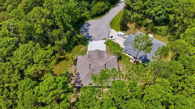 an aerial view of residential house with outdoor space and trees all around
