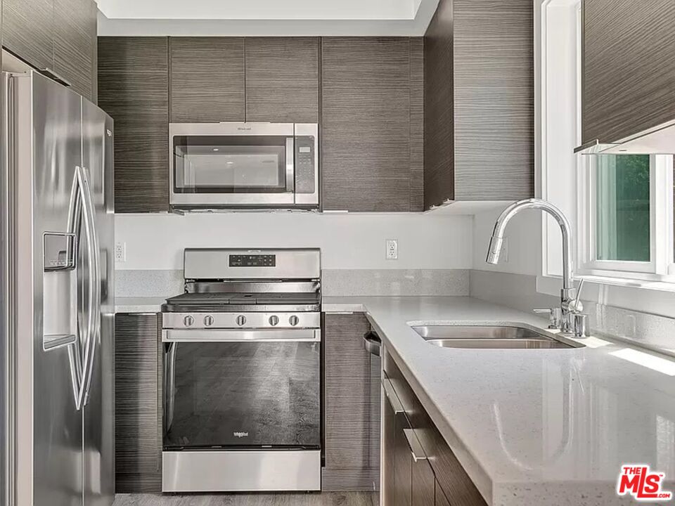 5750 Kester Avenue Van Nuys, CA 91411 - Photo 13 of 21 a kitchen with stainless steel appliances granite countertop a sink stove and refrigerator