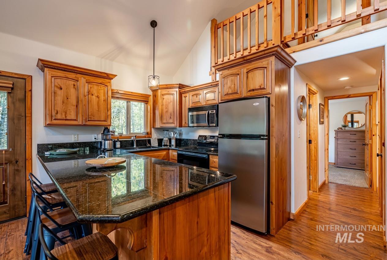 1409 Paul Bunyan Road McCall, ID 83638 - Photo 6 of 16 Kitchen with stainless steel appliances, a breakfast bar, dark stone counters, light wood finished floors, and wood finish cabinets