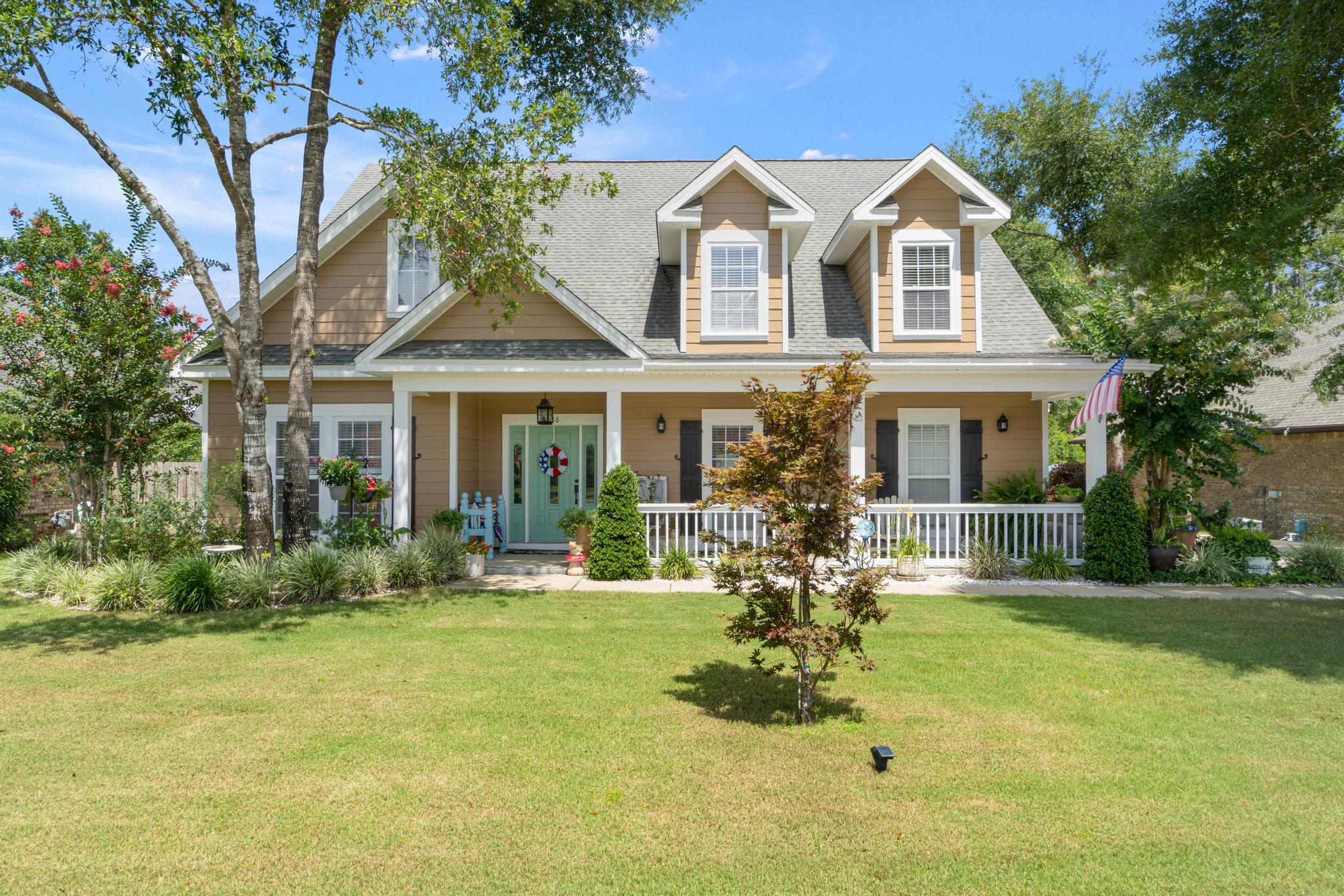 a front view of a house with a garden and trees