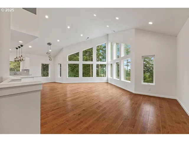a view of an empty room with wooden floor and windows
