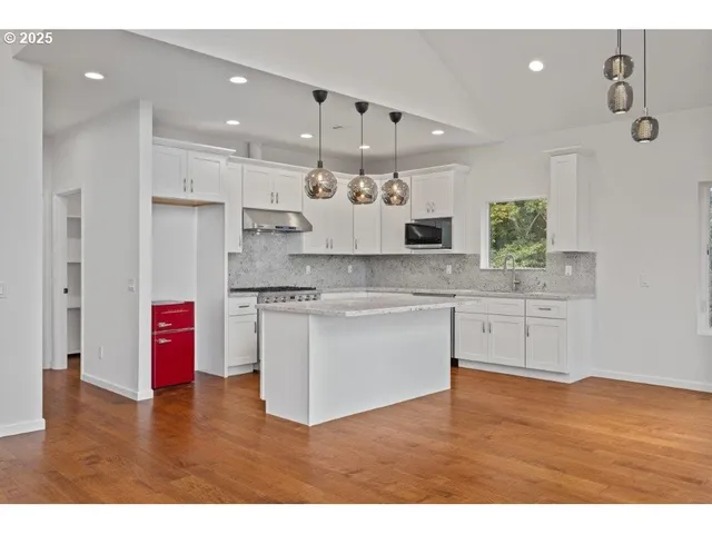 a kitchen with stainless steel appliances kitchen island granite countertop a stove a sink and a refrigerator