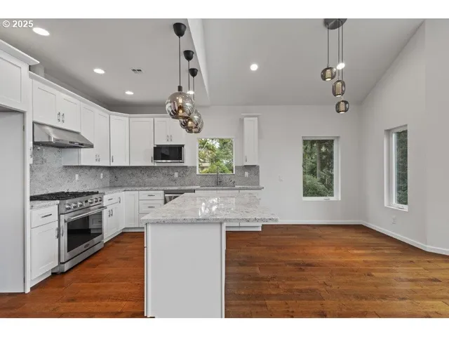 a kitchen with kitchen island granite countertop a sink cabinets and stainless steel appliances