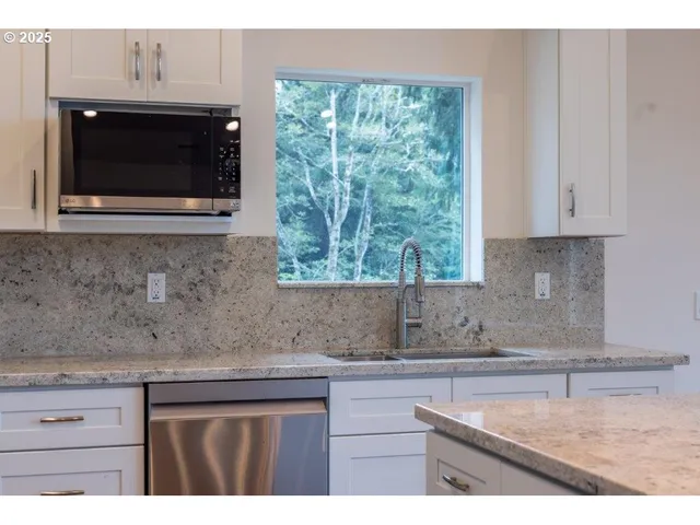 a kitchen with stainless steel appliances granite countertop white cabinets granite counter tops and a sink