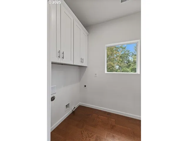 a view of an empty room with wooden floor and cabinets