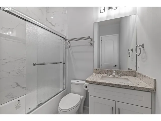 a bathroom with a granite countertop sink toilet a mirror and shower