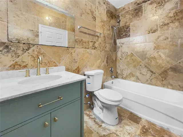 a view of a hallway with wooden floor and a bathroom