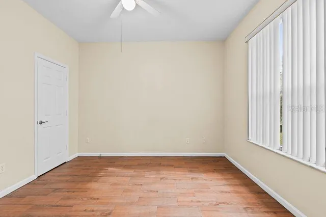 a view of an empty room with a window and wooden floor