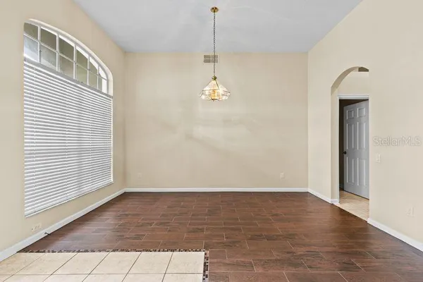 an empty room with wooden floor a ceiling fan and windows
