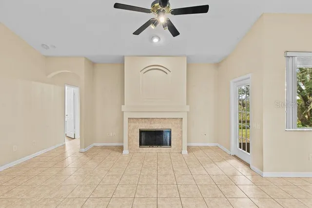 a view of an empty room with chandelier fan and fire place