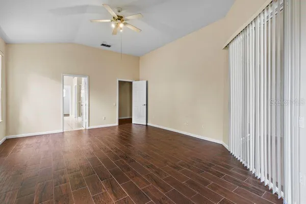 a view of an empty room with window and chandelier fan