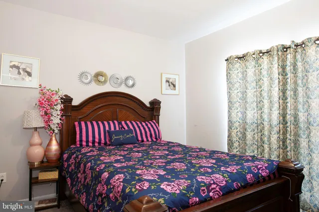 a bedroom with a bed and a dresser with curtain