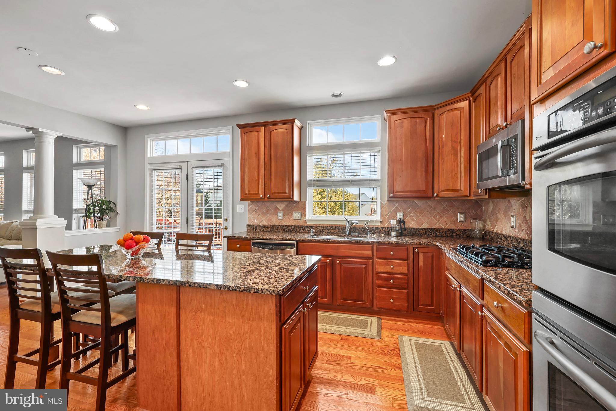 41742 Experience Way Aldie, VA 20105 - Photo 13 of 78 a kitchen with stainless steel appliances granite countertop wooden cabinets a sink a stove a dining table and chairs