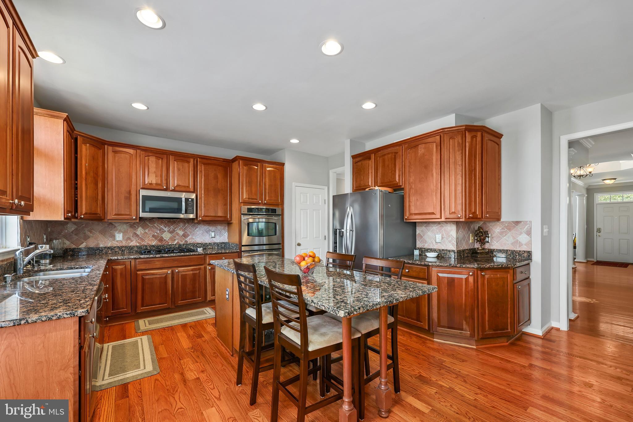41742 Experience Way Aldie, VA 20105 - Photo 14 of 78 a kitchen with stainless steel appliances granite countertop a stove top oven a sink dishwasher a dining table and chairs with wooden floor
