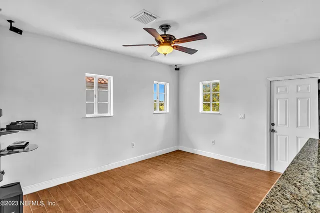 a view of empty room with window and wooden floor