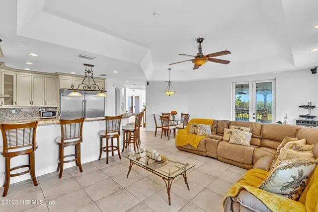 a kitchen with stainless steel appliances kitchen island granite countertop a dining table chairs and a refrigerator