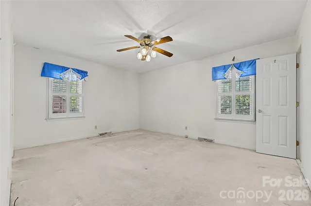 an empty room with closet and a chandelier fan