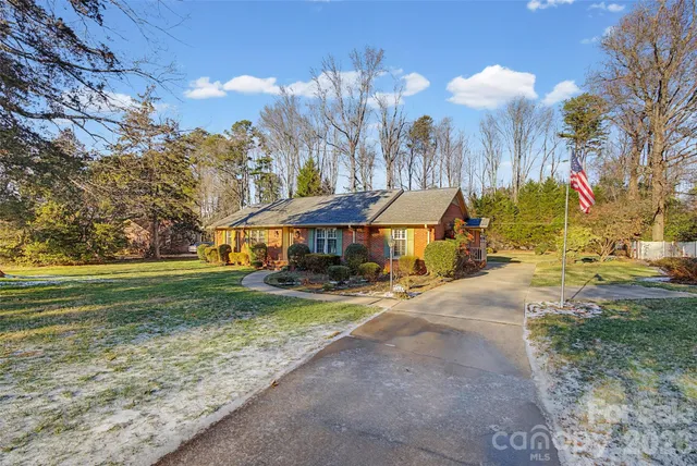 an aerial view of a house with a yard and trees all around