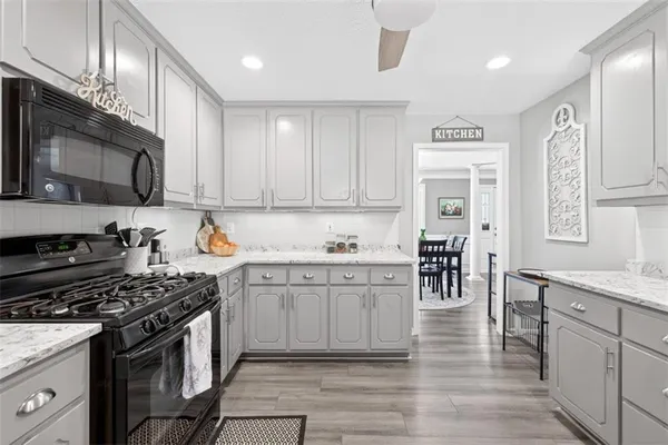 a kitchen with stainless steel appliances granite countertop a stove top oven a sink dishwasher a dining table and chairs with wooden floor