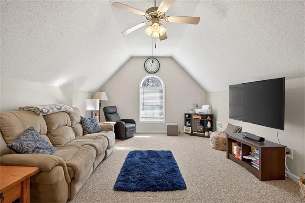 a living room with furniture a flat screen tv and a large window