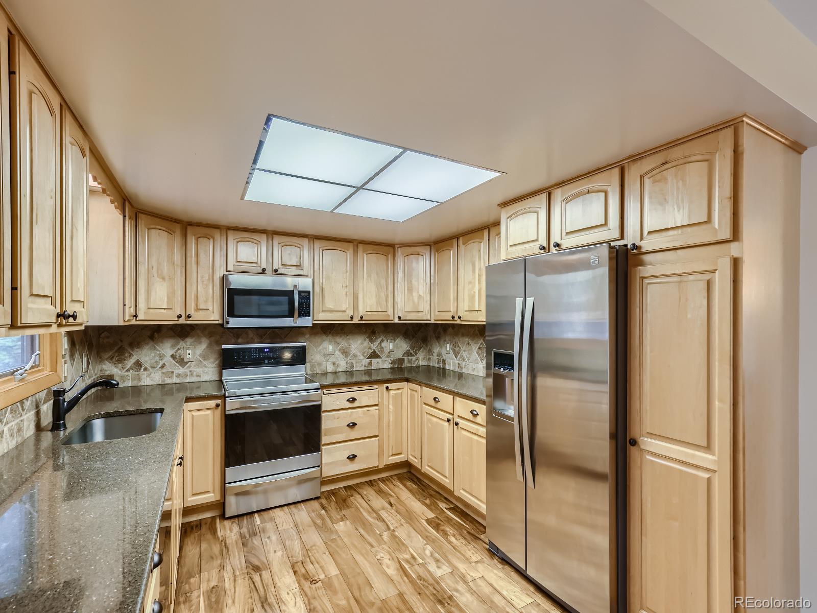 24697 Red Cloud Drive Conifer, CO 80433 - Photo 8 of 28 a kitchen with stainless steel appliances granite countertop a refrigerator a stove a sink and white cabinets with wooden floor