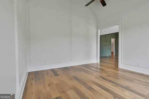 a view of an empty room with wooden floor and a bathroom