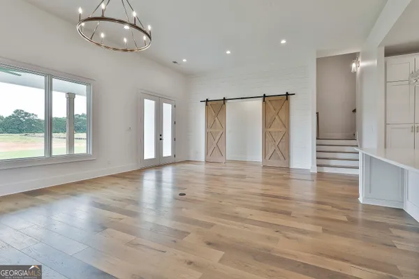an empty room with wooden floor fireplace and windows