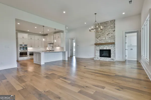 an empty room with wooden floor a fireplace and chandelier