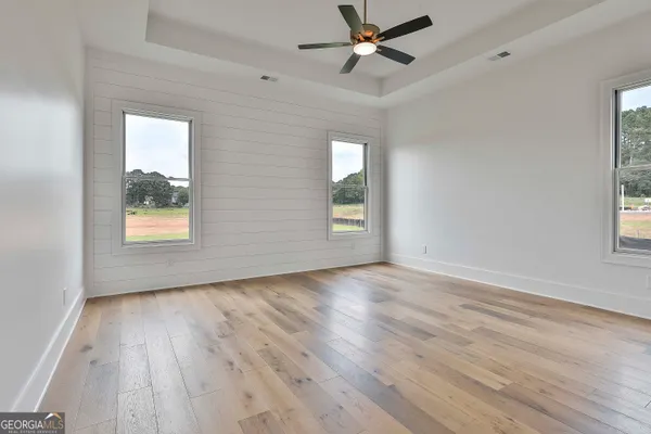 an empty room with wooden floor and windows