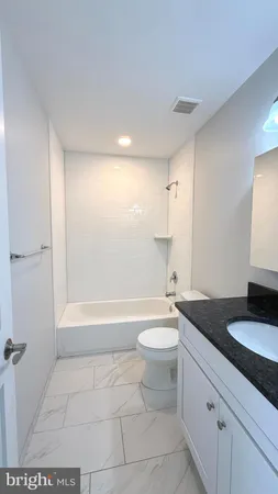 a bathroom with a granite countertop sink a toilet and bathtub